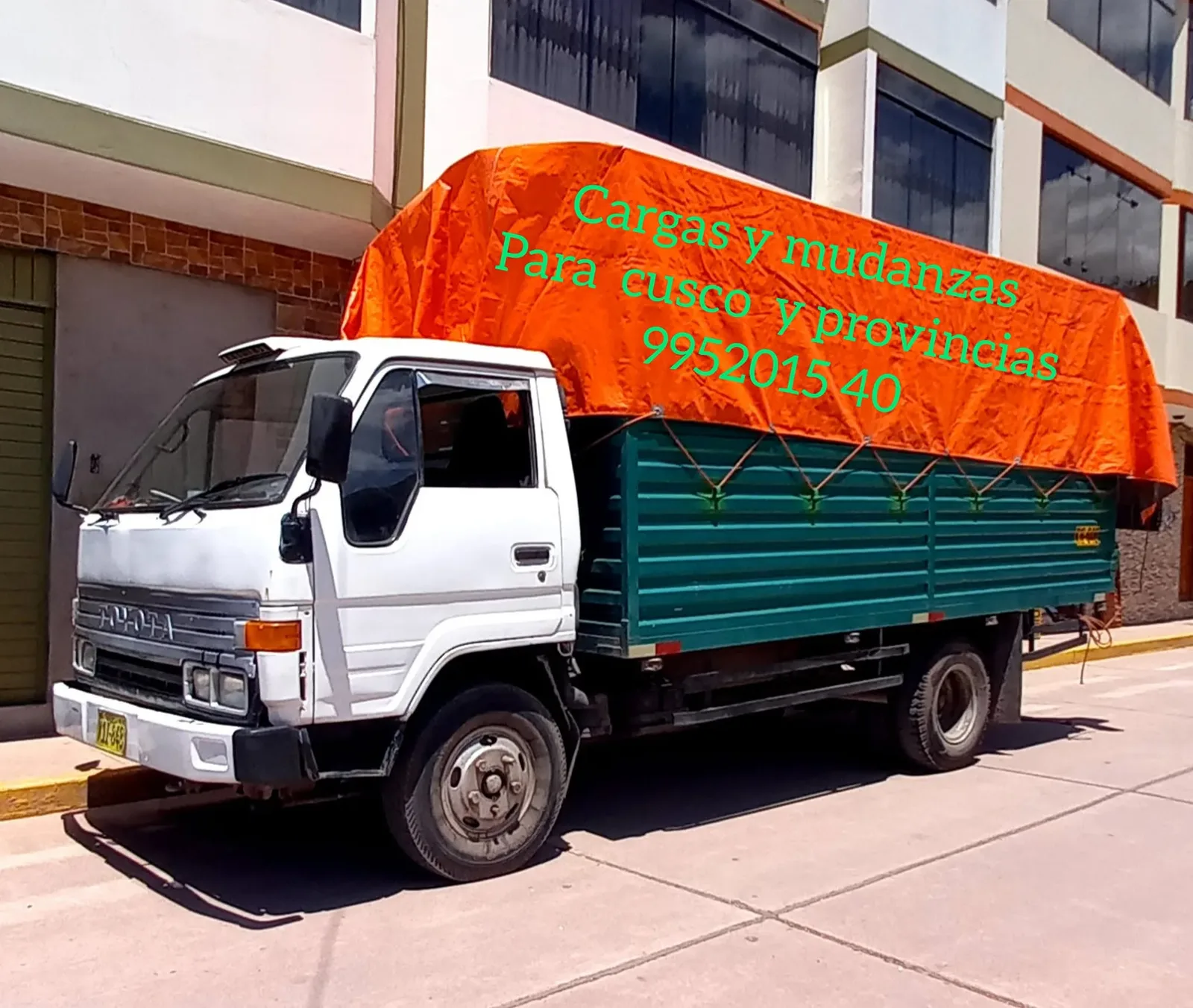 Camión de Mudaltoke con toldo naranja estacionado en una calle de Cusco