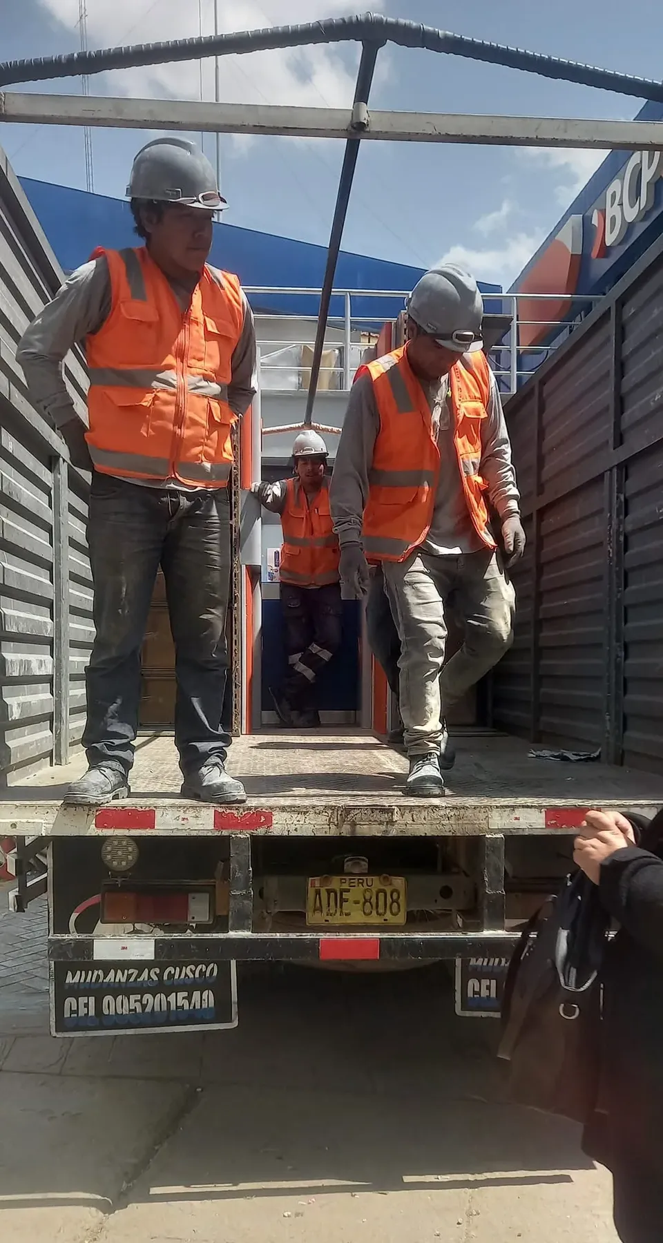Equipo de estiba con casco y chaleco sobre la plataforma del camión